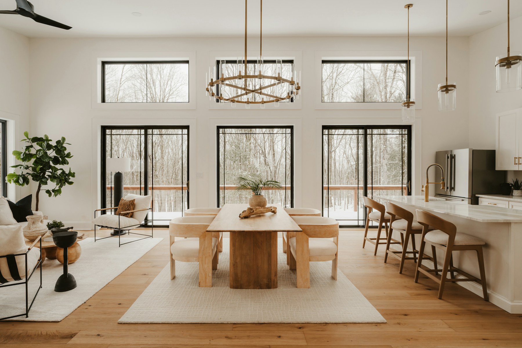 Bright photographed living and dining room with natural wood and winter trees