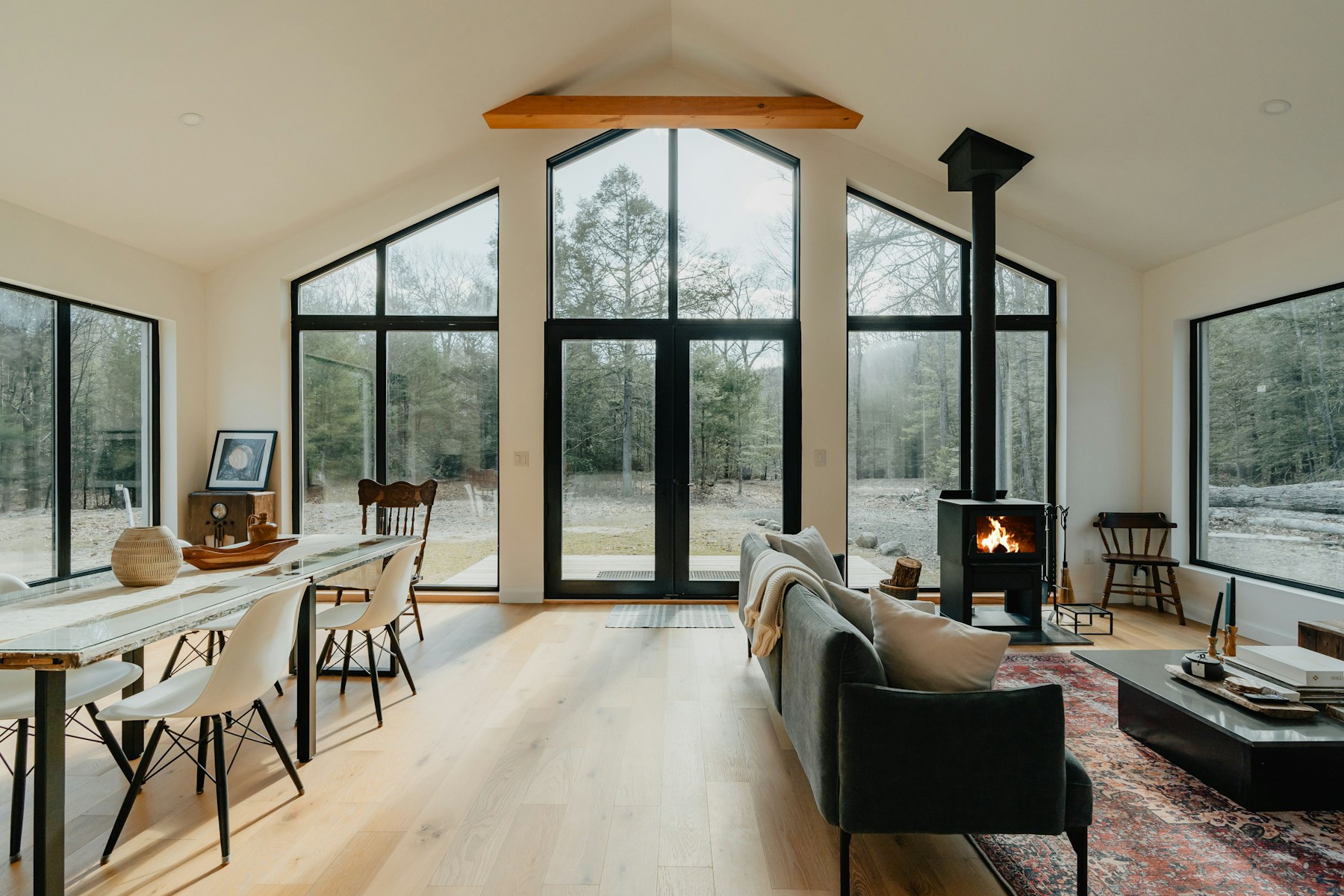 Professionally photographed modern vacation home with expansive forest-facing windows and a fireplace