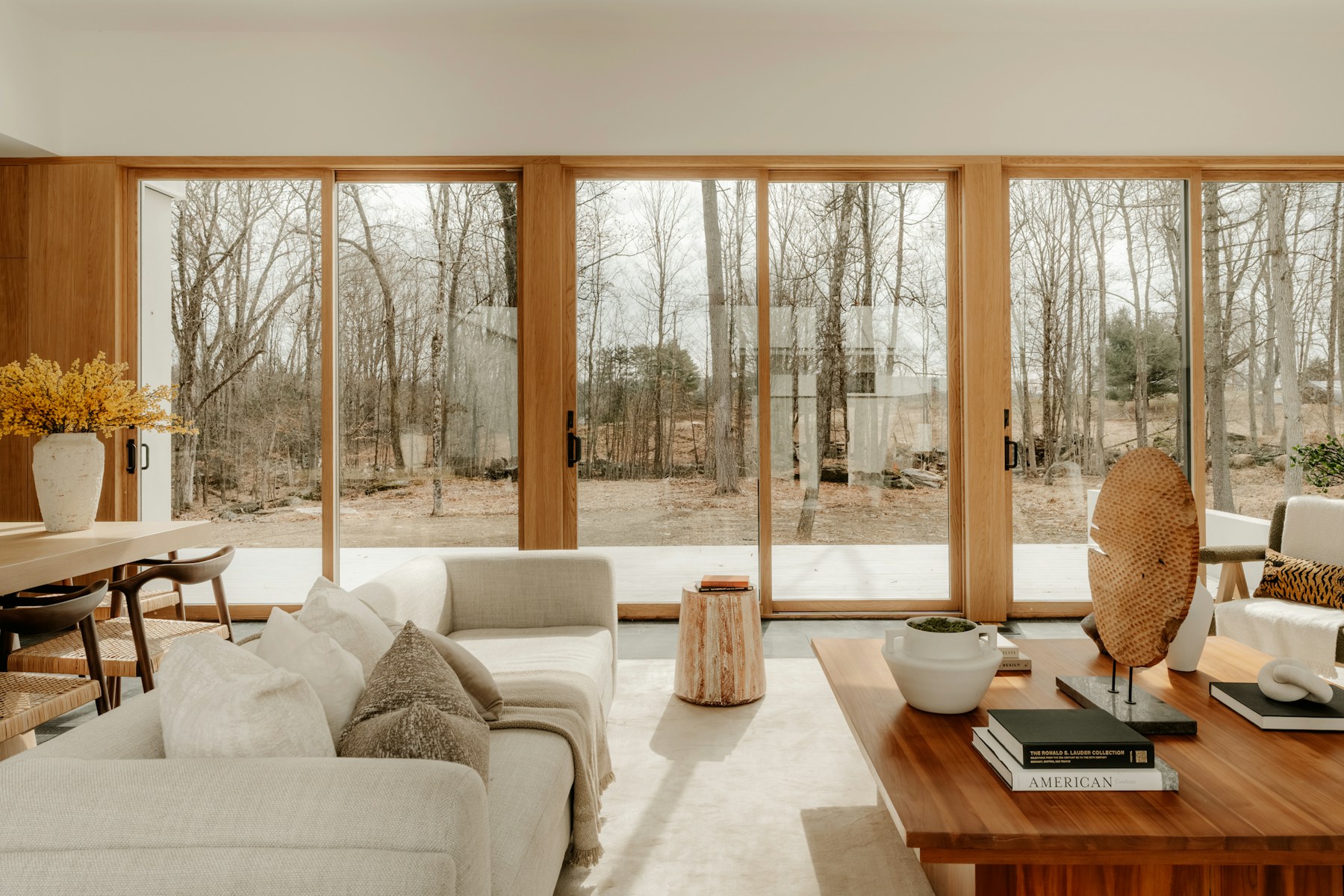 Bright, warm-toned living room with cream seating and large windows looking onto trees