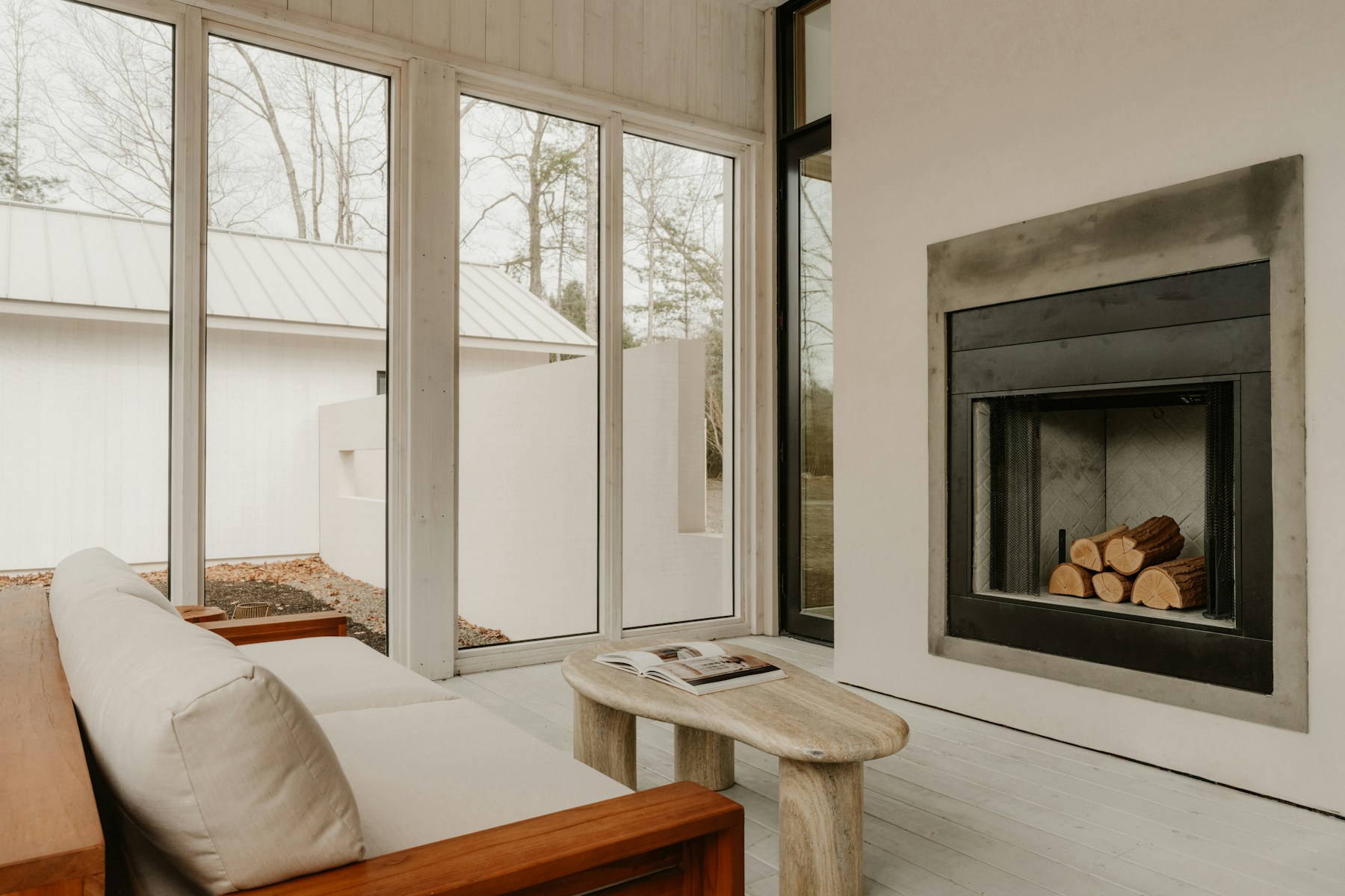 Bright photographed sunroom with pale wood furniture and a fireplace