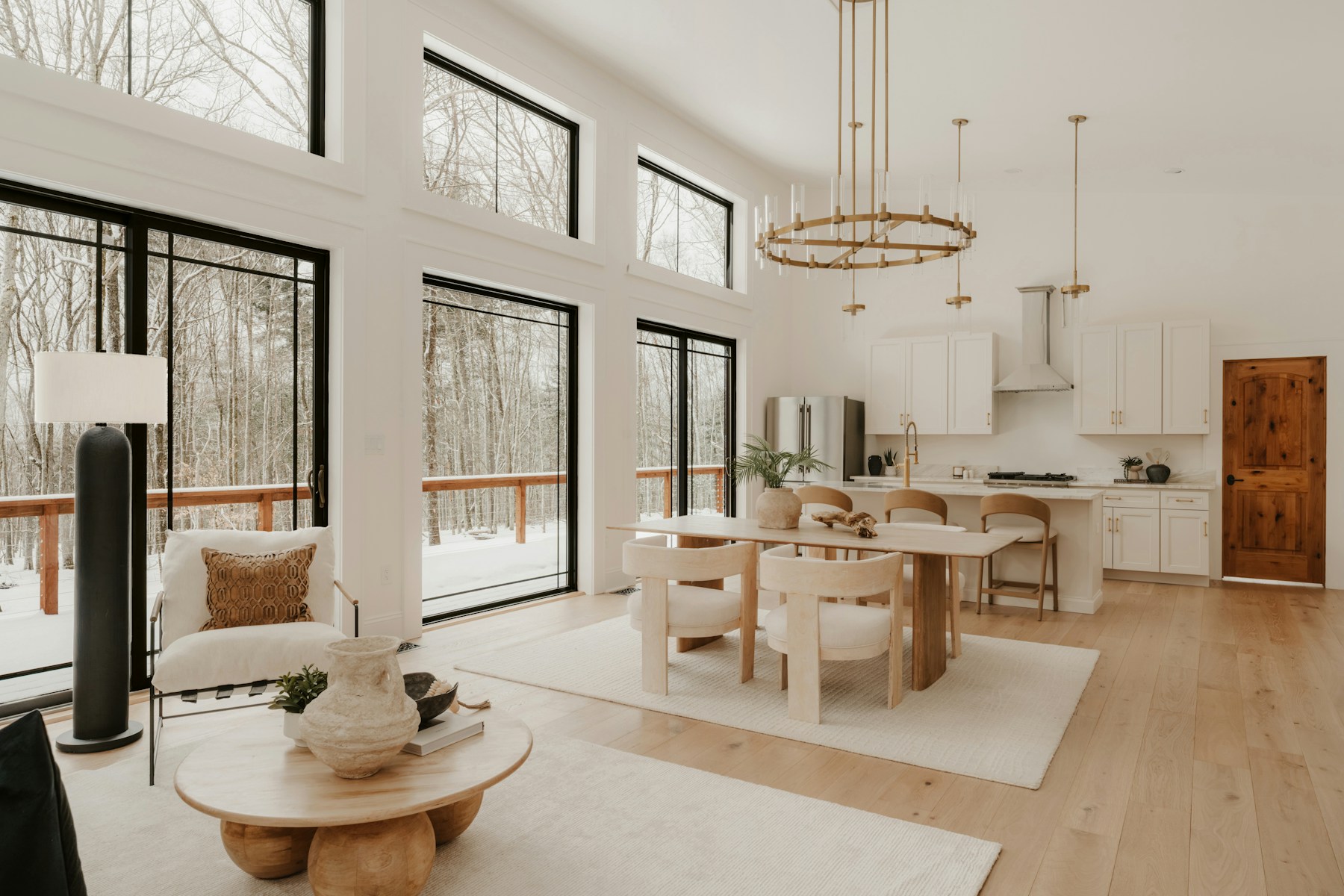 Sunlit living and dining room with winter trees outside